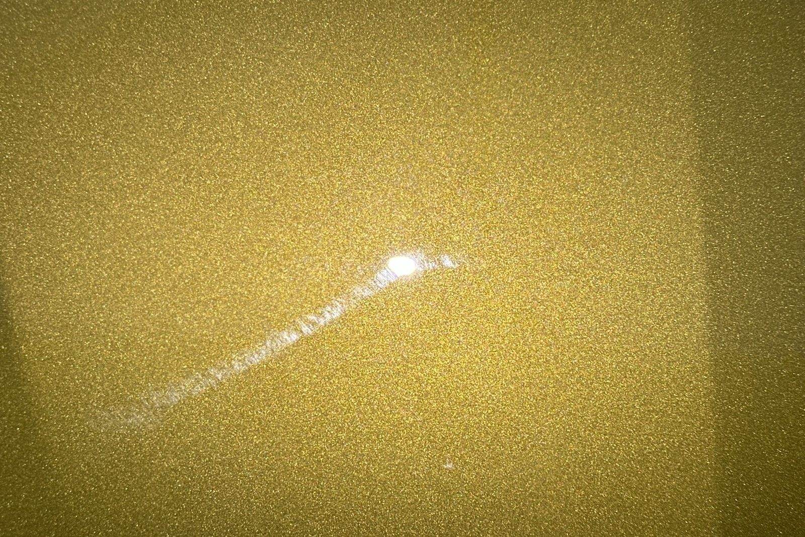 Gold metallic paint showing swirl marks and marring under direct light, before paint correction